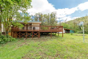 Back of house with a deck, a lawn, and a chimney