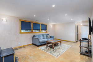 Living area with finished concrete floors, baseboards, and recessed lighting