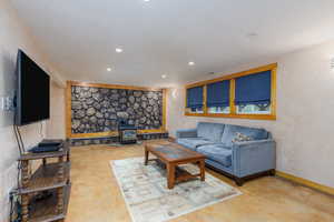 Living room featuring a wood stove, recessed lighting, baseboards, and concrete flooring