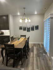 Dining room featuring dark wood finished floors, a chandelier, baseboards, and recessed lighting
