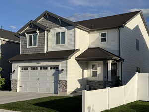 Craftsman inspired home with fence, a garage, stone siding, and concrete driveway