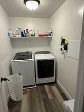 Laundry room with washing machine and clothes dryer, dark wood-style flooring, and baseboards