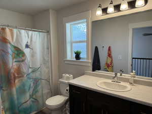 Bathroom with vanity, toilet, and curtained shower