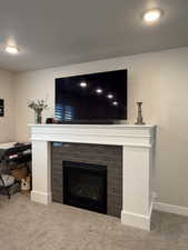 Detailed view of carpet flooring, a fireplace, and baseboards