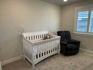 Carpeted bedroom with baseboards and a crib