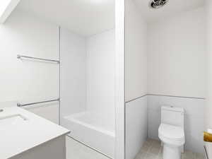 Bathroom featuring toilet, vanity, and shower / bath combination