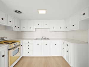 Kitchen featuring white electric stove, a sink, light countertops, and light wood-style floors