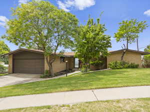 View of front of home with an attached garage, concrete driveway, brick siding, and a front lawn