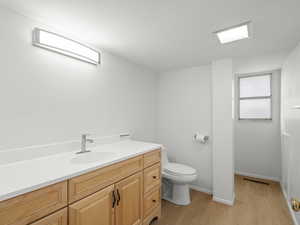 Bathroom with wood finished floors, toilet, vanity, and baseboards