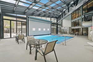 Indoor pool with a pergola, a hot tub, a patio, and outdoor dining area