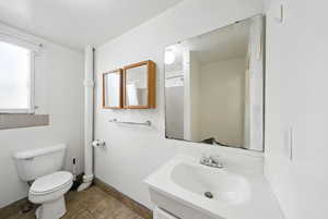 Bathroom with toilet, vanity, baseboards, and a shower with curtain