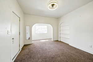 Unfurnished room featuring carpet floors, baseboards, and built in shelves