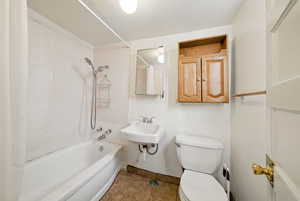 Full bath with toilet, shower / bath combo with shower curtain, tile patterned flooring, baseboards, and a sink
