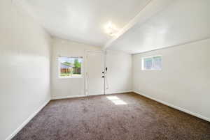 Unfurnished room with carpet flooring, lofted ceiling, and baseboards