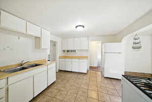 Kitchen with white appliances, a sink, white cabinets, and light tile patterned floors