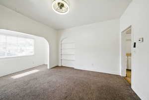 Spare room with carpet flooring, built in shelves, and baseboards