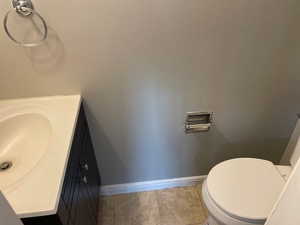 Bathroom with baseboards, vanity, tile patterned flooring, and toilet