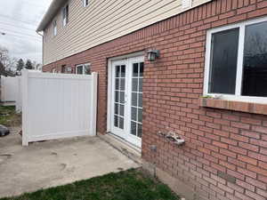 View of side of property with french doors, brick siding, and a patio area