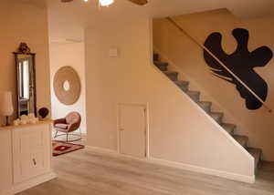 Stairway featuring ceiling fan, wood finished floors, and baseboards