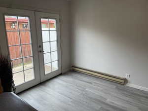 Entryway with a baseboard heating unit, french doors, wood finished floors, and baseboards