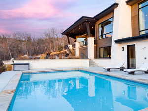 Pool at dusk featuring stairway, an outdoor pool, and a patio area