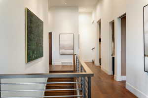 Stairway featuring wood finished floors, a high ceiling, and baseboards