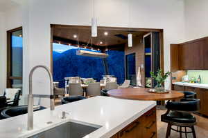 Kitchen with a sink, light countertops, modern cabinets, wooden walls, and brown cabinets