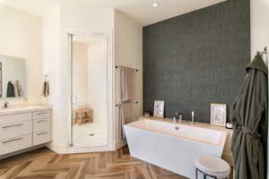 Bathroom featuring a stall shower, an accent wall, recessed lighting, a freestanding tub, and vanity