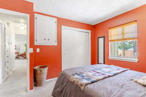 Bedroom featuring light carpet, a textured ceiling,  a closet, and additional built in cabinet