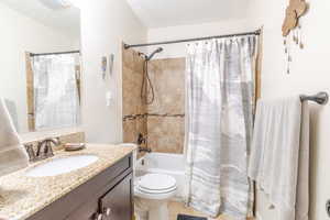 Bathroom featuring vanity, shower / bath combo, toilet, tile patterned floors, and a textured ceiling