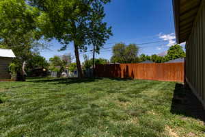 View of yard, mature trees, and fence