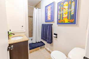 Bathroom featuring toilet, a shower stall, vanity, and tile patterned flooring