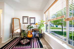 View of large open plan living room, featuring large windows, white walls, and light carpeting