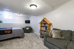 Bedroom with full size closet, carpet floors, a textured ceiling, and baseboards