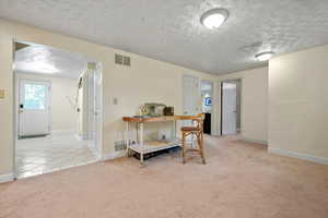 Carpeted office with baseboards, a textured ceiling, and tile patterned flooring