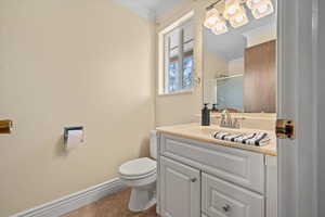 Bathroom featuring crown molding, toilet, vanity, baseboards, and tile patterned floors