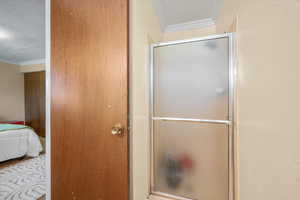 Ensuite bathroom with crown molding, a shower stall, and a textured ceiling