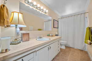 Bathroom featuring crown molding, vanity, toilet, tile patterned floors, and a shower with shower curtain