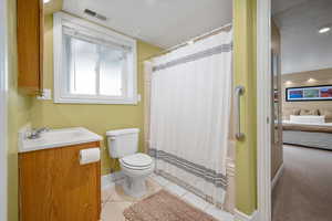 Full bath featuring toilet, ensuite bathroom, baseboards, vanity, and tile patterned floors
