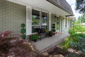 Doorway to property with covered porch and brick siding