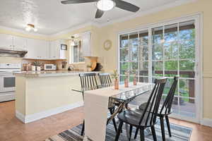 Dining room featuring plenty of natural light, a ceiling fan, crown molding, and light tile patterned floors