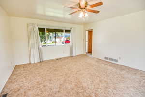 Carpeted spare room featuring ceiling fan