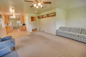 Unfurnished living room featuring light colored carpet, a ceiling fan, recessed lighting, and a chandelier