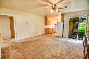 Kitchen with white appliances, light colored carpet, a ceiling fan, and under cabinet range hood