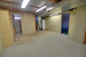 Below grade area featuring water heater, heating unit, and carpet
