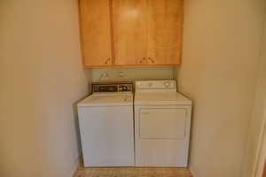 Washroom featuring independent washer and dryer, cabinet space, and baseboards