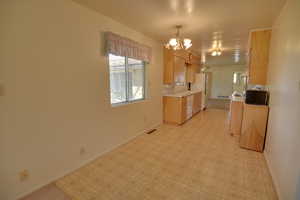 Kitchen with white appliances, light countertops, a chandelier, baseboards, and light floors