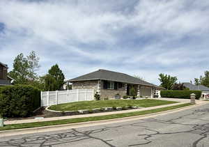 Single story home featuring an attached garage, brick siding, driveway, and roof with shingles