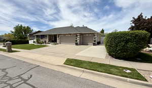 Ranch-style home with a garage, concrete driveway, and a front yard