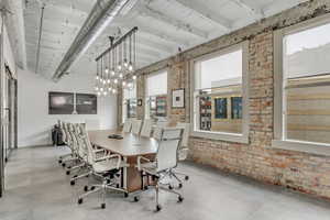 Dining area featuring finished concrete flooring, brick wall, and a chandelier